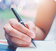 Close up of someone&#39;s hand who is holding a pen and writing in a book